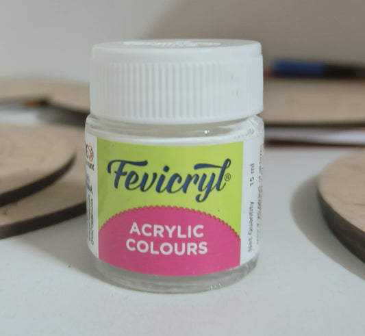 A 15ml fevicryl acrylic bottle with white paint placed on a table with mdf cutouts scattered on the table.