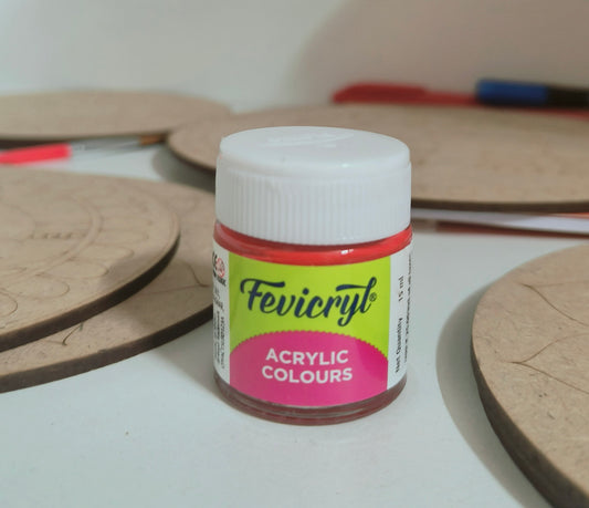 A 15ml fevicryl acrylic bottle with red paint placed on a table with mdf cutouts scattered on the table.