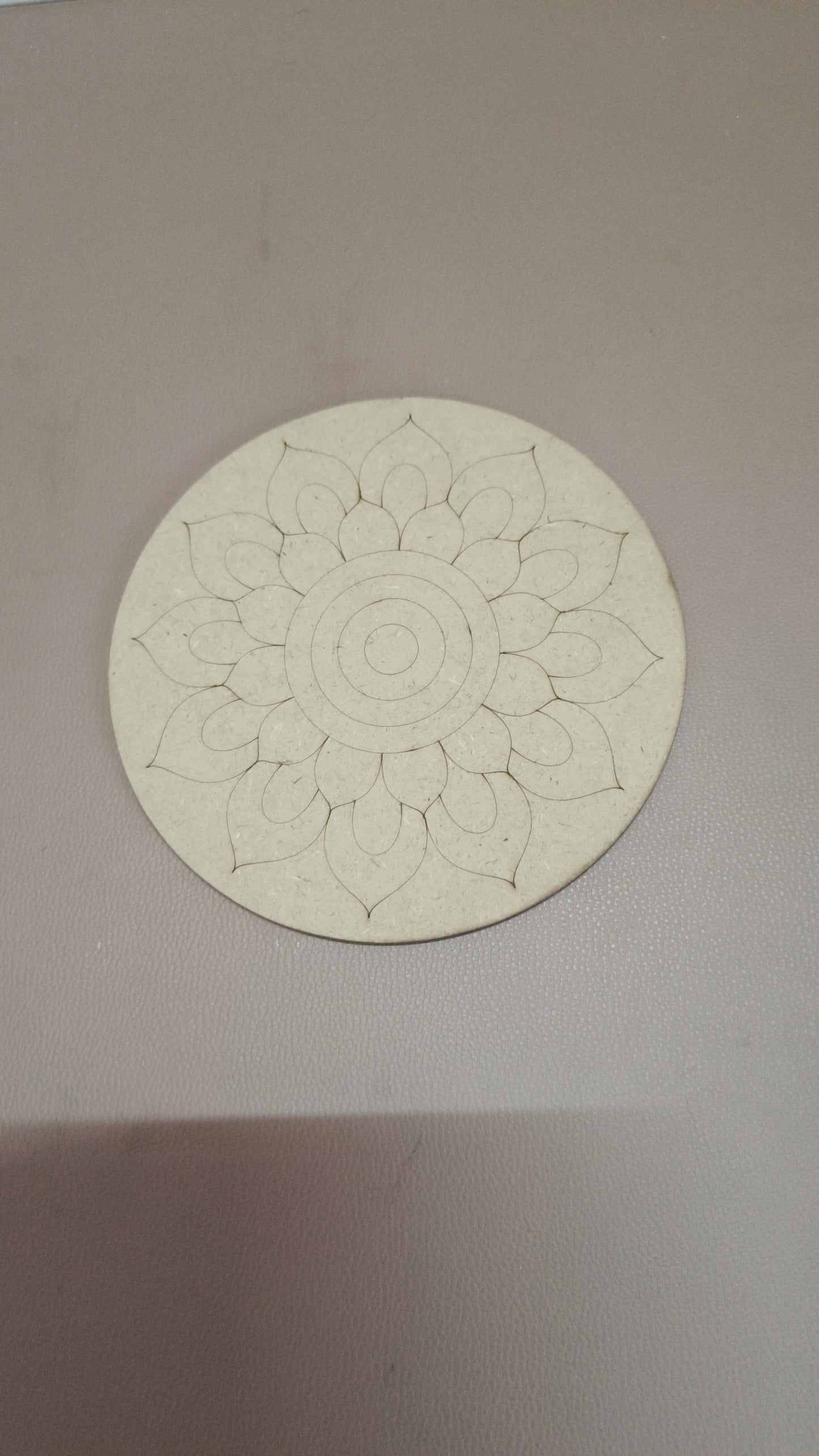 A round MDF board with flower design on a brown background.