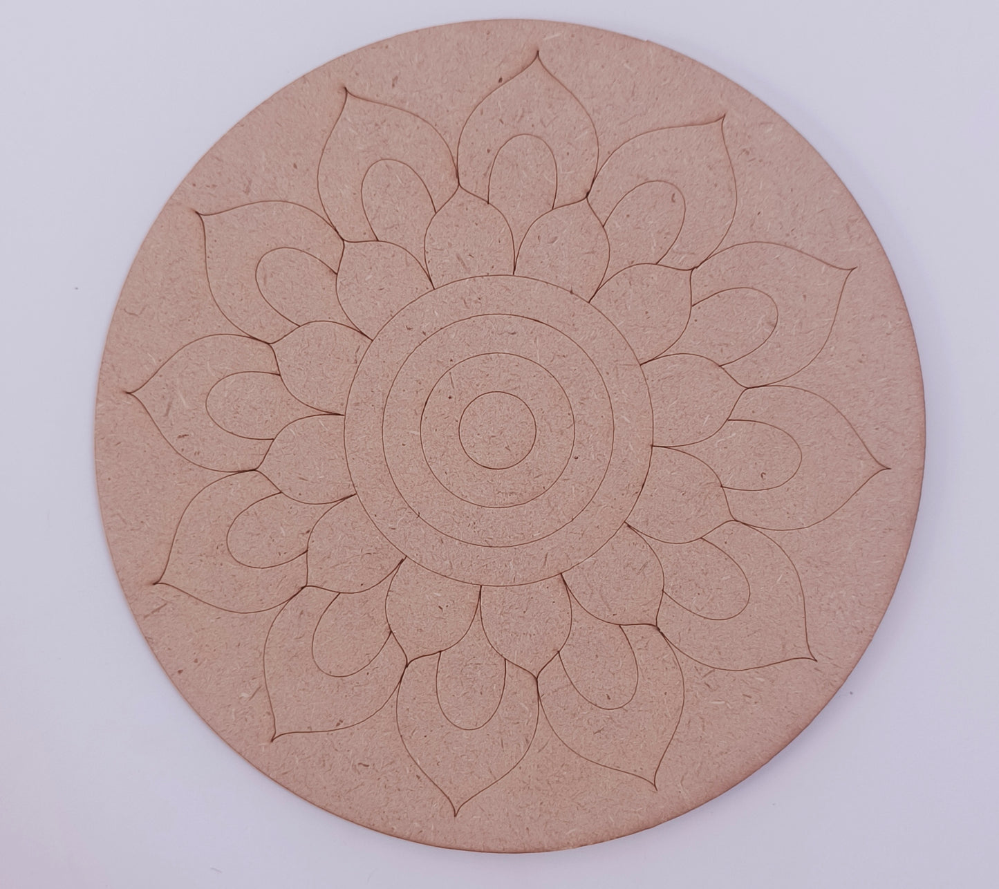 A round MDF cutout with flower design placed on a white background.