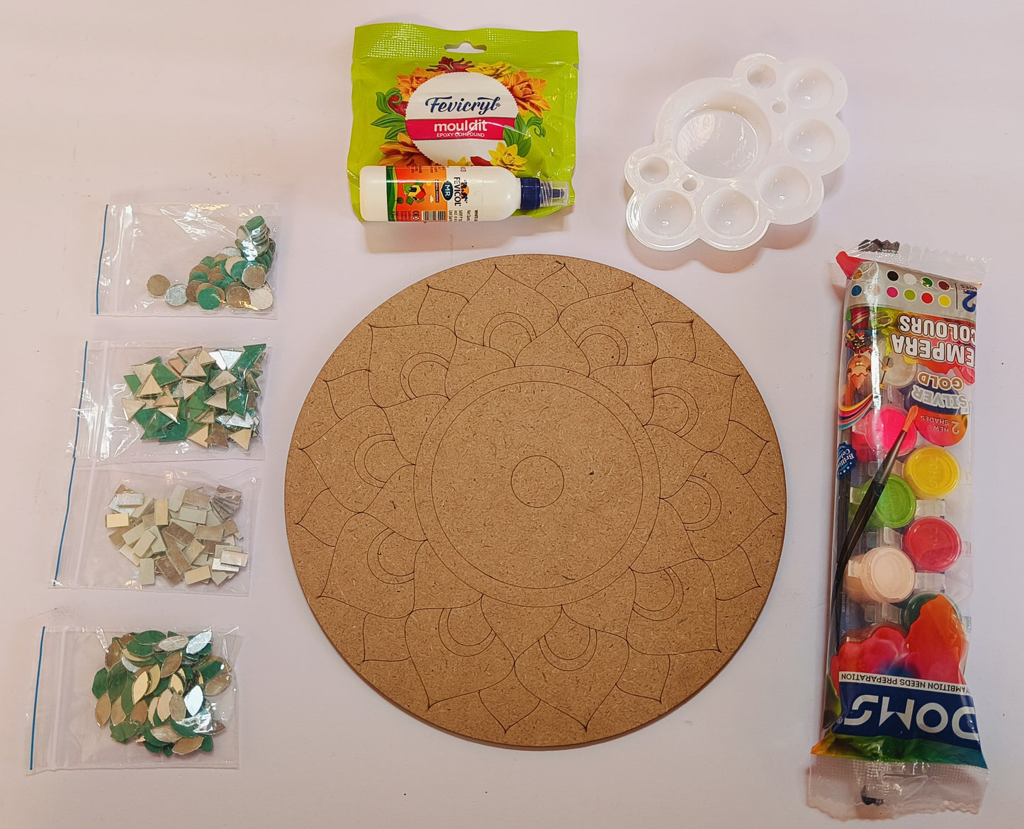 A round MDF board with mandala design, 4 packets for mirrors in assorted shapes, a white palate, DOMS tempera colors packet, a fevicryl mouldit packet and a fevicol bottle - all placed on a white background.